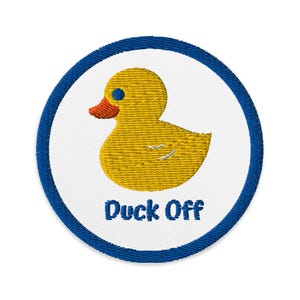 May include: Embroidered patch featuring a yellow rubber duck with an orange beak and blue eye, set against a white background. The patch has a blue border and the words "Duck Off" in blue.