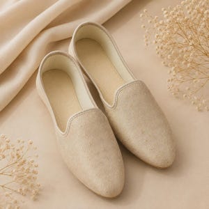 May include: A pair of beige slip-on loafers featuring a subtle diamond-patterned texture on the exterior. The shoes have a rounded toe, a low-cut topline, and a light-colored interior lining, presenting a clean and uniform monochromatic appearance.
