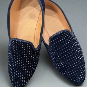 May include: A pair of navy blue loafers with a studded design. The shoes have a rounded toe and a low heel. The interior is a light tan color.
