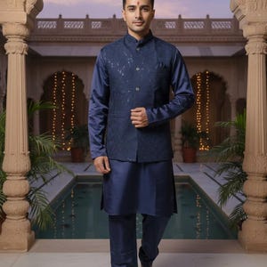 May include: A navy blue three-piece suit. The outfit includes a long-sleeved shirt, a vest with sequin detailing, and matching pants. The ensemble is made of a shiny fabric. The person is standing in a courtyard with a pool.