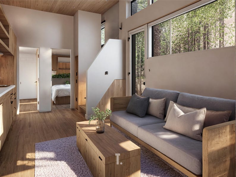 May include: Interior shot of a modern living space with wooden furniture and flooring. A gray sofa with decorative pillows sits against a neutral wall, with a wooden coffee table in front. Large windows offer a view of trees.