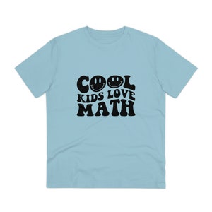 Puede incluir: Una camiseta azul claro con un gráfico negro que dice "COOL KIDS LOVE MATH" con dos caras sonrientes en la palabra "COOL".