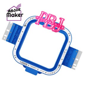 May include: A blue and white embroidery hoop with a pink glittery "DRJ monogramming" accent. The hoop has a rectangular shape with blue plastic components and white markings. The "ABODE Maker" logo is in the upper left corner.