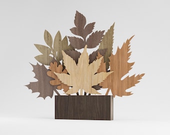 Peut inclure: Sculpture de feuilles en bois représentant différentes formes et couleurs de feuilles, dont des feuilles d'érable et de chêne. Les feuilles sont disposées en forme de bouquet et placées dans une base rectangulaire marron foncé. La sculpture est en bois et a un aspect naturel et rustique.