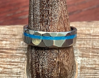 Custom hamered tungsten ring with a thin offset channel filled with blue glow powder.
