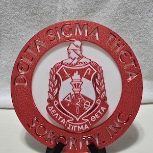 以下が含まれることがあります： 赤と白のデルタシグマシータソラリティ、インクのエンブレム。円形のエンブレムは、縁にソラリティの名前が付いています。中央には、ギリシャ文字とトーチが付いたシールドがあります。