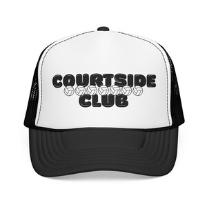 May include: A white and black trucker hat featuring the text COURTSIDE CLUB in a bold, rounded black font. Between the two words, there is a horizontal row of seven small black and white volleyball icons printed on the front foam panel.