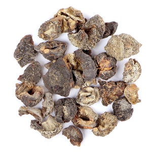 Puede incluir: Primer plano de trozos de fruta seca, marrón y gris. Los trozos de fruta están esparcidos sobre un fondo blanco.