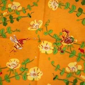 May include: A vibrant orange fabric featuring a repeating pattern of yellow flowers with green stems and leaves. The design includes small illustrations of a flying bee and a tiny character sitting within a flower, rendered in red and yellow tones.