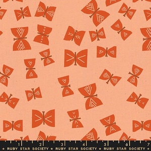 Może przedstawiać: Brzoskwiniowa tkanina z powtarzającym się wzorem pomarańczowych motyli z białymi geometrycznymi wzorami. Motyle różnią się rozmiarem i orientacją. Na dole znajduje się linijka z napisem "RUBY STAR SOCIETY".