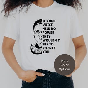 May include: White t-shirt with a black and white image of Ruth Bader Ginsburg and the text "If your voice held no power they wouldn't try to silence you".