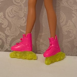 May include: A pair of pink roller skates with yellow wheels. The skates have a high-top design and are made of plastic.