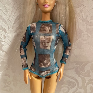 May include: A blue mesh bodysuit with a pattern of faces printed on it. The bodysuit has long sleeves and a scoop neck.