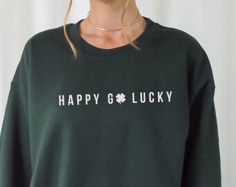 May include: A dark green sweatshirt with the text "HAPPY GO LUCKY" and a four-leaf clover graphic printed in white.