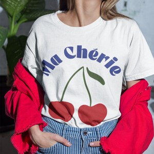 May include: White t-shirt with a blue and green graphic of two cherries and the text "Ma Ch&eacute;rie".