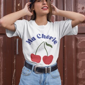 May include: White t-shirt with a graphic of two red cherries and the text "Ma Ch&eacute;rie" in blue.