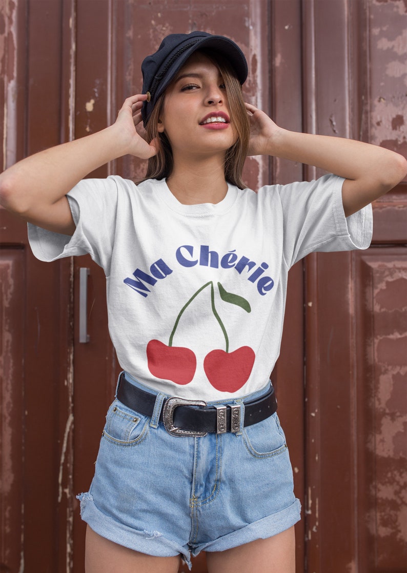 May include: White t-shirt with a graphic of two red cherries and the text "Ma Ch&eacute;rie" in blue.