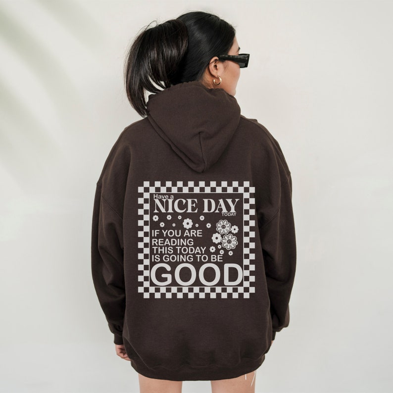 May include: Brown hooded sweatshirt with a white graphic print that says "Have a NICE DAY TODAY IF YOU ARE READING THIS TODAY IS GOING TO BE GOOD" with a checkered background.