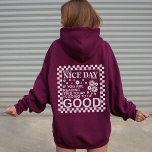 May include: Burgundy hooded sweatshirt with a white checkered graphic that says "Have a Nice Day Today" and "If you are reading this today is going to be good".
