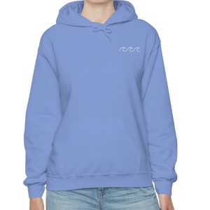 May include: A light blue hooded sweatshirt with a white wave design on the front.