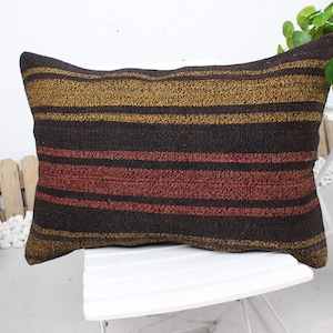 May include: A striped throw pillow with brown, red, and gold stripes. The pillow is made of a woven fabric and has a rectangular shape.