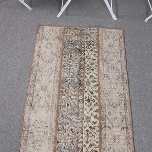 May include: Rectangular rug with a distressed, vintage look. The rug features a central panel with floral and geometric patterns in shades of brown, gray, and beige. The edges are bordered with a darker brown trim, creating a cohesive design.