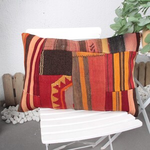 May include: A colorful patchwork pillow with red, orange, brown, and yellow stripes. The pillow is made of woven fabric and has a rustic, bohemian style.