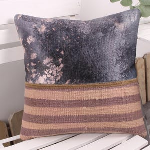 May include: A decorative pillow with a two-tone design. The top half features a dark, mottled pattern with light accents, while the bottom half has horizontal stripes in shades of brown and tan. A thin, gold-colored band separates the two sections.