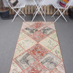 May include: A rectangular patchwork rug with a diamond pattern. The rug is made of different colored fabrics, including beige, pink, and red. The rug has a fringe border.
