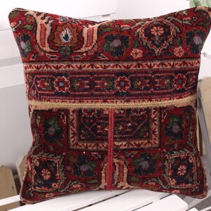 May include: A decorative pillow with a traditional, patterned design. The pillow features a rich color palette of red, brown, and beige, with intricate floral and geometric motifs. The pillow is square-shaped and appears to be made of a woven fabric.