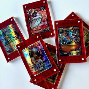 Może przedstawiać: Pięć kart kolekcjonerskich Pokemon w czerwonych akrylowych wyświetlaczach. Karty przedstawiają postacie Volcarona V, Entei GX, Charizard i Charizard. Karty są holograficzne i mają r&oacute;żne kolory, w tym czerwony, niebieski, ż&oacute;łty i zielony.