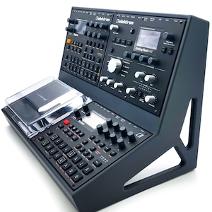 Puede incluir: Sintetizador Elektron Analog Heat MkII negro con una caja de ritmos Elektron Digitakt negra y una caja de ritmos Elektron Analog Rytm negra en un soporte negro.
