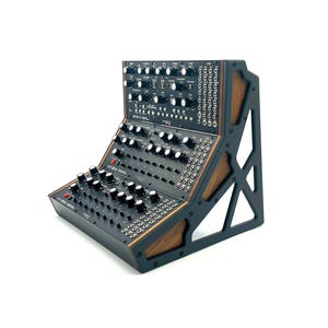 May include: A black synthesizer with numerous knobs and buttons, featuring a wooden frame. The instrument has multiple rows of controls and is designed for electronic music production. The synthesizer is angled for easy access and use.
