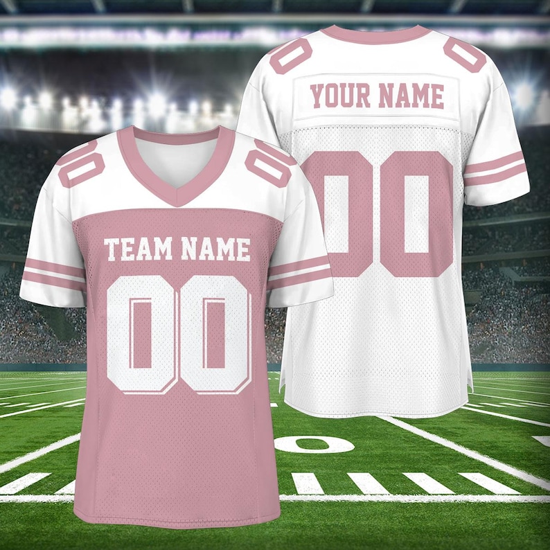 Puede incluir: Dos camisetas de f&uacute;tbol rosa y blancas con el texto "YOUR NAME" y "TEAM NAME" en ellas. Las camisetas tienen n&uacute;meros blancos.