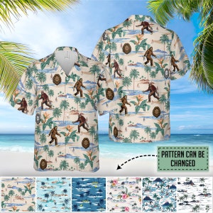 May include: A beige button-up shirt with a tropical print featuring palm trees, sailboats, and a Bigfoot-like creature. The shirt has a white background with green palm trees, blue sailboats, and brown Bigfoot figures. The text "PATTERN CAN BE CHANGED" is visible in the image. The shirt is shown on a model in front of a beach scene.