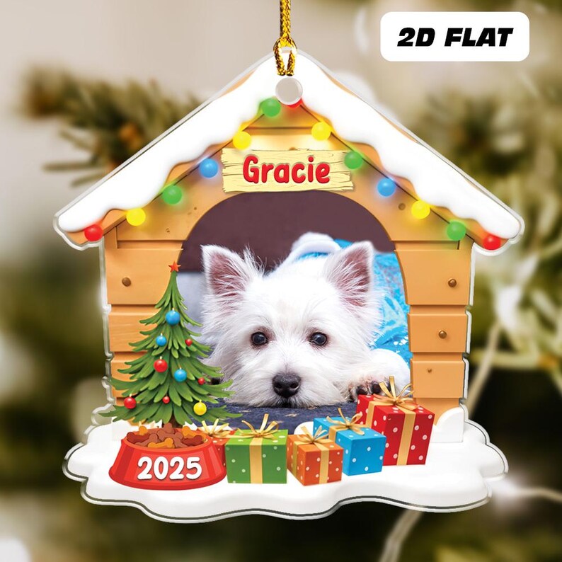 May include: A 2D flat Christmas ornament featuring a white dog named Gracie inside a wooden dog house. The ornament includes a Christmas tree, presents, and a dog bowl with the year 2025.