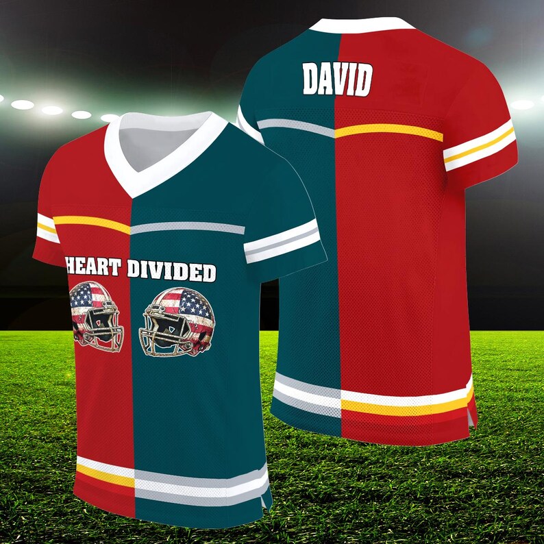 Op de afbeelding: Twee voetbaltruien, een rode en een teal, met een witte en grijze streep aan de onderkant. De rode trui heeft de naam "DAVID" op de rug. De teal trui heeft de tekst "HEART DIVIDED" en twee Amerikaanse voetbalhelmen met Amerikaanse vlaggen.