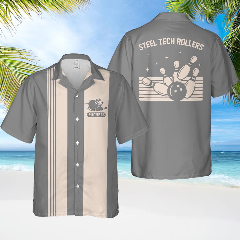 May include: Grey bowling shirt with a cream central panel and vertical stripes. The shirt features a bowling ball and pins graphic with the name "MICHELE" on the front. The back of the shirt has the text "STEEL TECH ROLLERS" and a bowling graphic.