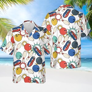 May include: White short-sleeved button-down shirt with a bowling-themed pattern. The design features bowling pins, bowling balls, and bowling shoes in red, blue, yellow, and teal, set against a white background. The shirt has a classic collar and a relaxed fit.