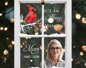 May include: A rectangular white window frame ornament featuring a red cardinal on a snowy branch, the text I Am Always With You, and a portrait of a person with glasses. Below the text Mom and the years 1956-2026 are printed with a small heart.