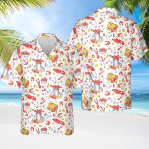 May include: White button-up shirt with a colorful pattern of crawfish, lemons, and other seafood. The shirt has short sleeves and a relaxed fit.