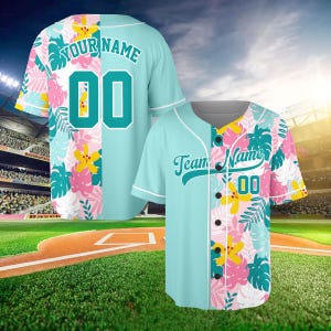 May include: A light blue baseball jersey featuring a tropical floral pattern in pink, yellow, and teal. The front displays the text Team Name and the number 00, while the back shows the text Your Name and the number 00 in teal lettering.
