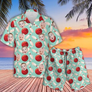 May include: A matching bowling-themed shirt and shorts set. The light blue set features a pattern of red bowling balls, white bowling pins, and baby faces. The shirt has a button-down front and short sleeves. The shorts have a drawstring waist.