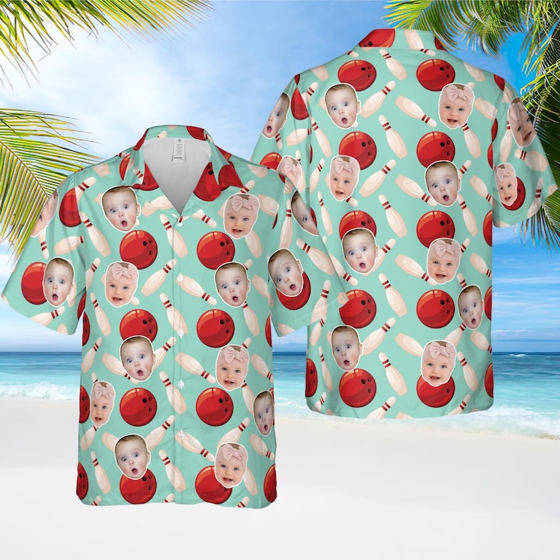 May include: A short-sleeved button-down shirt with a bowling theme. The shirt features a light teal background with a pattern of red bowling balls, white bowling pins, and baby faces. The shirt has a classic collar and a relaxed fit.