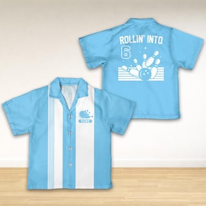 May include: Light blue bowling shirt with white vertical stripes and a bowling pin graphic. The shirt has the text "ROLLIN' INTO 6" on the back. The front of the shirt has a bowling pin graphic and the word "NAME".