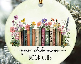 May include: Round ceramic ornament with a floral and book design. The ornament features a row of colorful books with names on the spines, surrounded by flowers. The text "your club name BOOK CLUB" is written in black script.