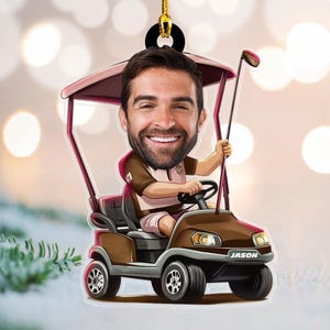 May include: A brown golf cart Christmas ornament features a caricature of a person's face. The golf cart has a burgundy canopy and the name 