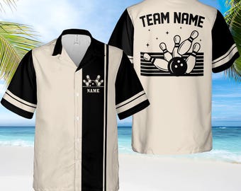 May include: A beige and black bowling themed button-up shirt with short sleeves. The front of the shirt has a black stripe down the center with a bowling pin and ball graphic. The back of the shirt has the text "TEAM NAME" with a bowling pin and ball graphic.
