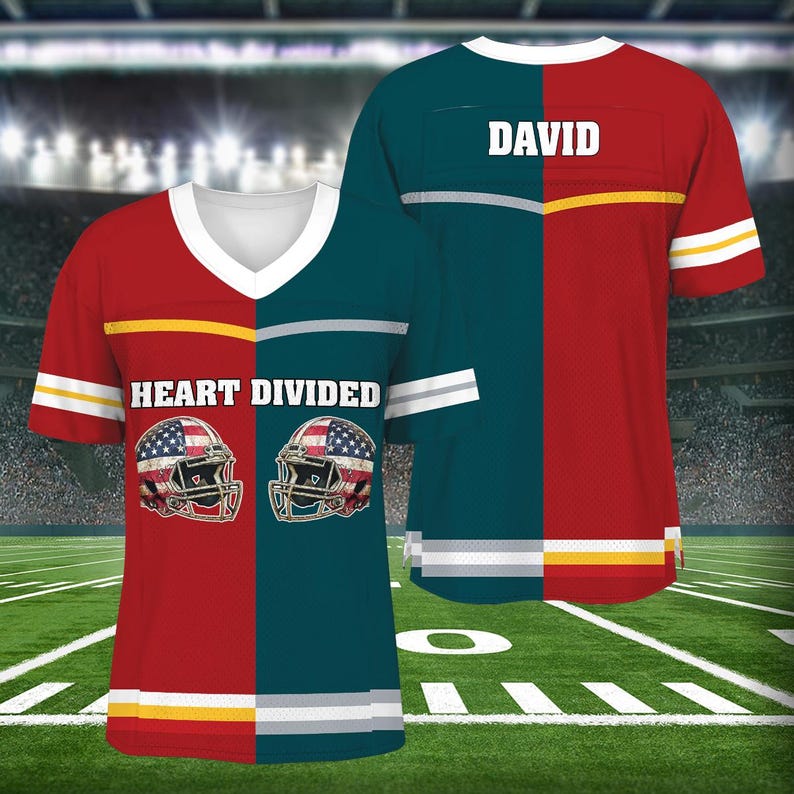 Op de afbeelding: Een rood en groen shirt met de tekst "HEART DIVIDED" en twee American football helmen met Amerikaanse vlaggen. Het shirt heeft een witte streep over de borst en een gele streep over de onderkant. Het shirt heeft ook de naam "DAVID" op de rug.