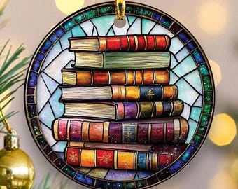 Peut inclure: Ornement de Noël rond représentant une pile de livres aux dos colorés. Les livres sont empilés, avec un fond de style vitrail dans les tons de bleu, vert et blanc. L'ornement est doté d'une boucle dorée pour l'accrocher.